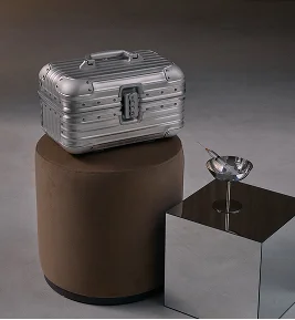 Silver ribbed beauty case on brown cylindrical pedestal with metallic flower accent on display box - Instagram in Montreal, QC