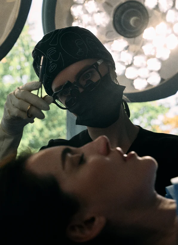 Doctor Emily Deane holds a medical tool to the client's face during professional beauty treatment session - in Montreal, QC