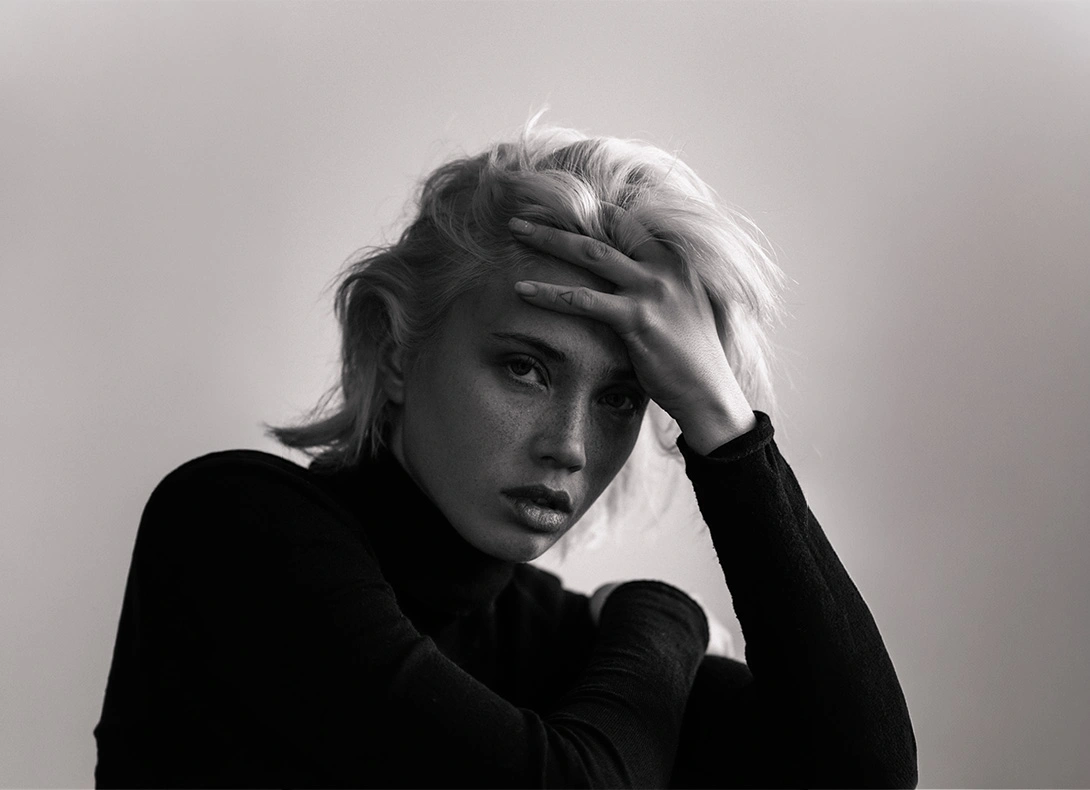 Black and white portrait of blonde woman with hand on forehead in contemplative pose. - Alar base reduction in Montreal, QC