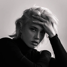 Woman with blonde hair touching forehead showing facial features in black and white portrait - Alar base reduction alarplasty in Montreal, QC