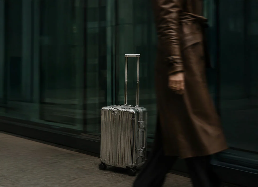 Traveler walking through a luxury hotel or airport hallway beside a sleek silver suitcase in a cinematic travel scene. - Out of Town Services