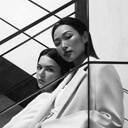 Two women with clear skin posing behind geometric black lines in monochrome beauty portrait - Advanced acne scar treatment in Montreal, QC