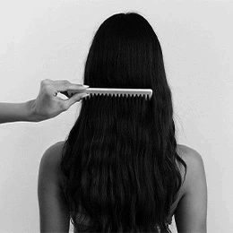 Woman with long dark hair being combed during PRP hair treatment consultation in black and white - Female hairloss in Montreal, QC