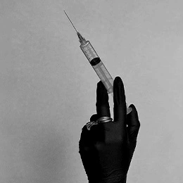 Hand holding medical syringe with needle for cosmetic injection procedure in black and white - Tear through fillers in Montreal, QC
