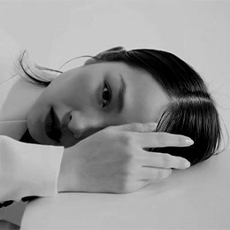 Woman resting head on hand showing smooth lower eyelid area in black and white portrait - Asian eyelid surgery in Montreal, QC