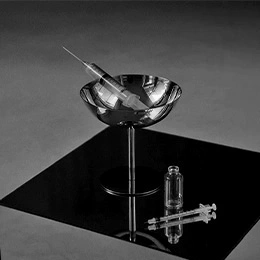 Modern glass bowl sink with chrome faucet and medical syringes on black surface for ultrasound-guided injectable procedures - Dermal fillers in Montreal, QC