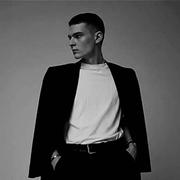 Young androgynous model in black blazer and white shirt showcasing refined facial features in monochrome portrait - Male rhinoplasty in Montreal, QC